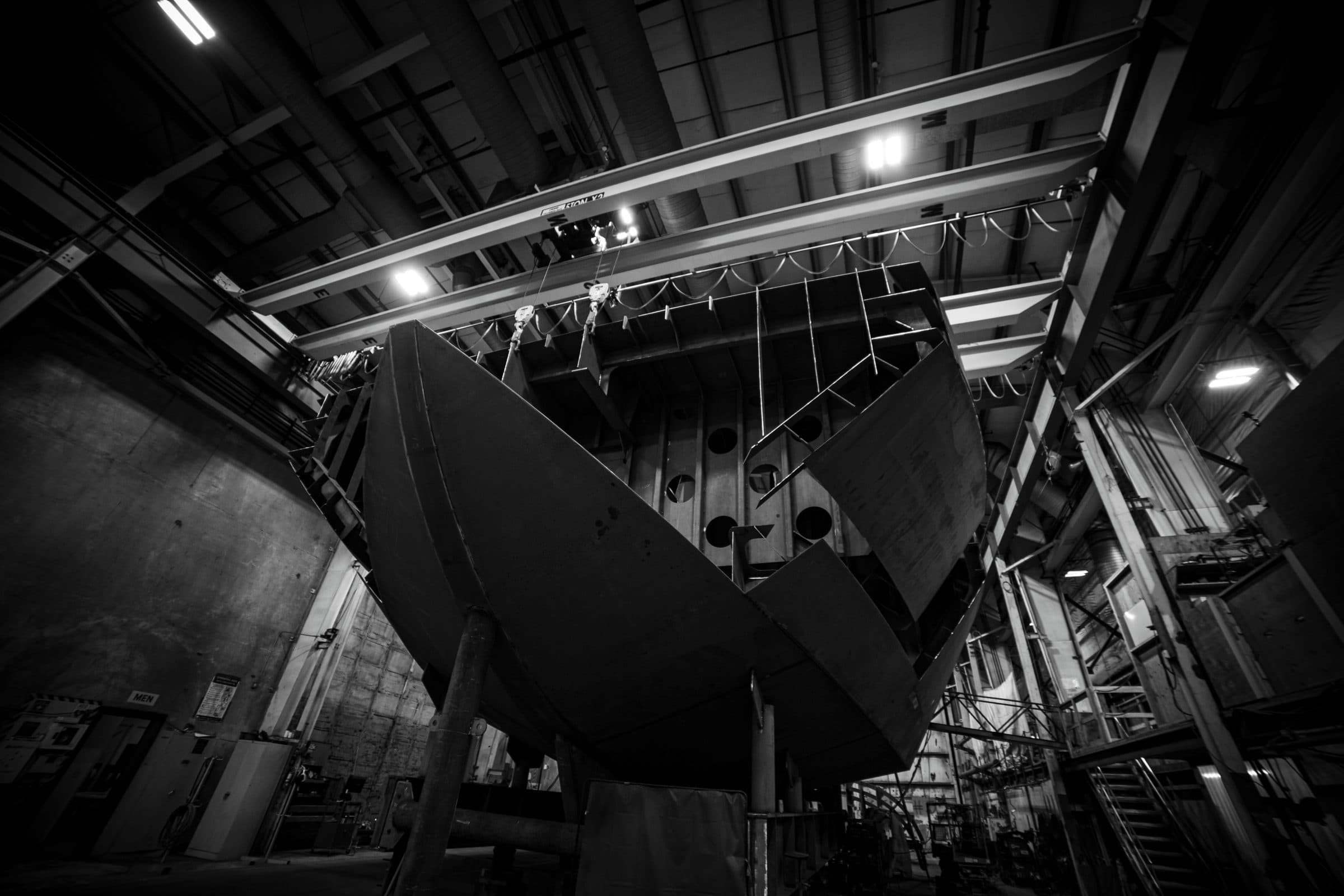 Tuuli C’s bare steel hull suspended by overhead crane during assembly.