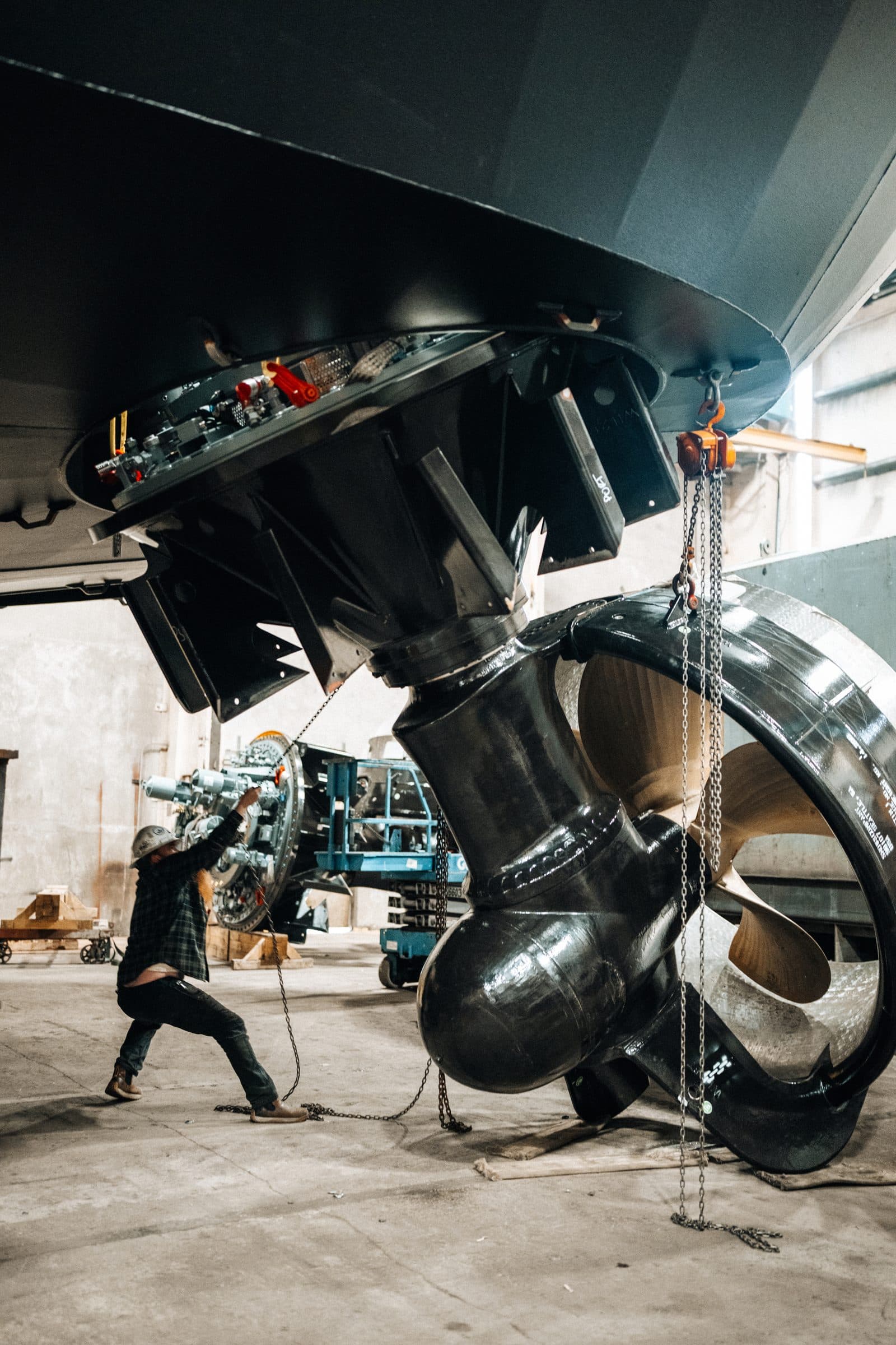 Technician installing azimuth thruster unit into hull mount.