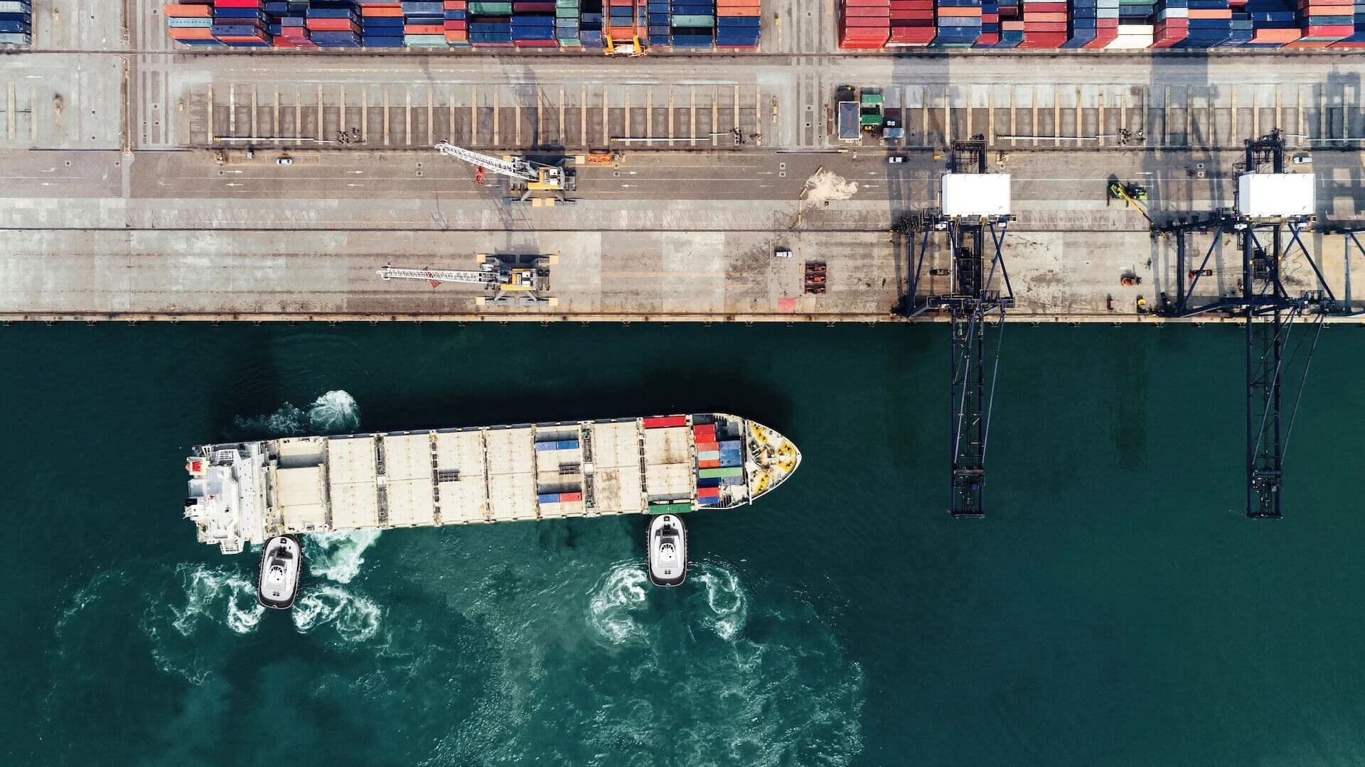 An aerial photograph of a work boat turning in the water.