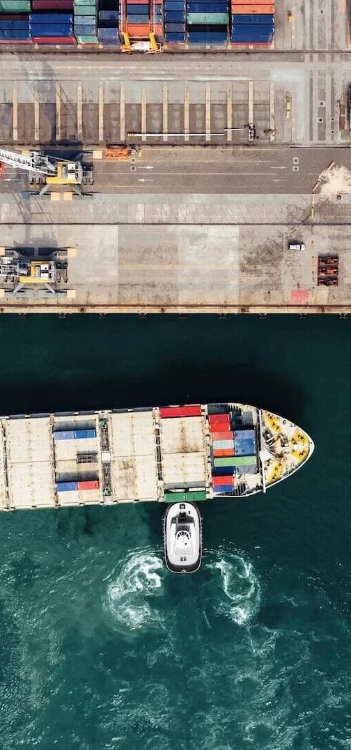 An aerial photograph of a work boat turning in the water.