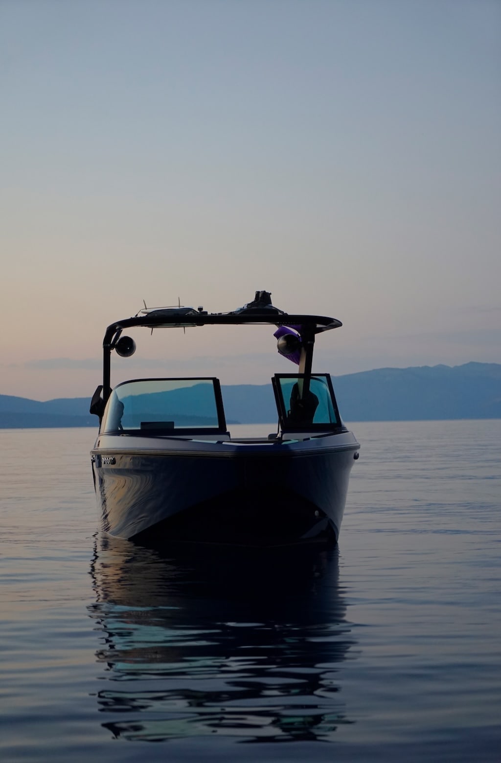 A photograph of a boat floating on a lake at dusk time.