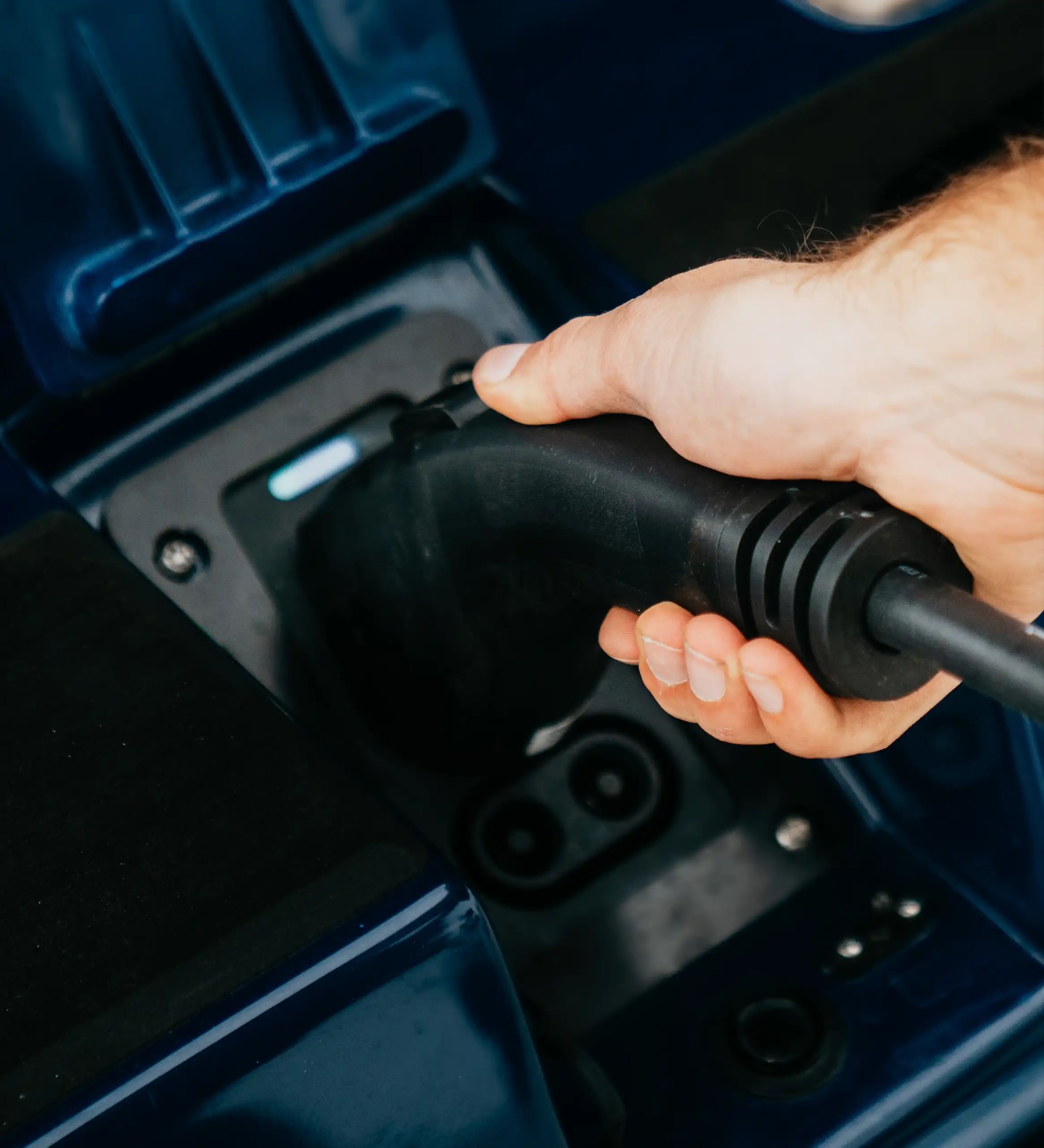 A photograph of a hand plugging in a charging cord into an EV boat.