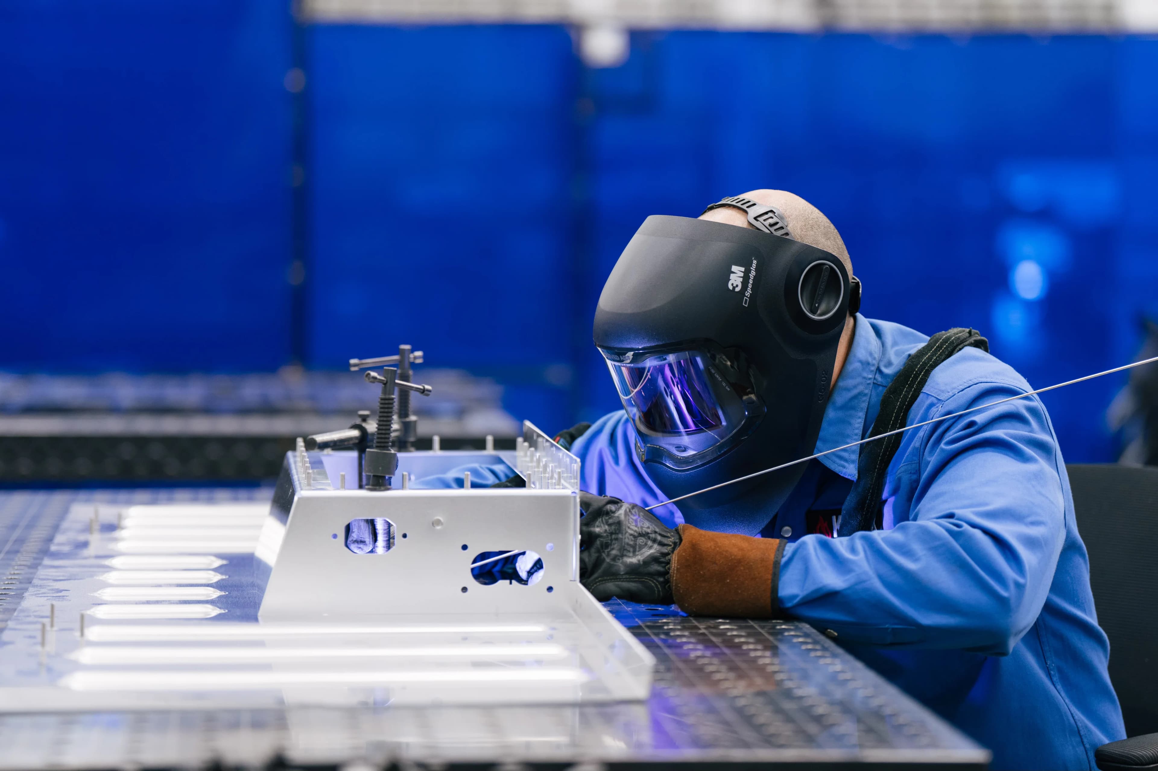 A photograph of a man welding in a factory in the US
