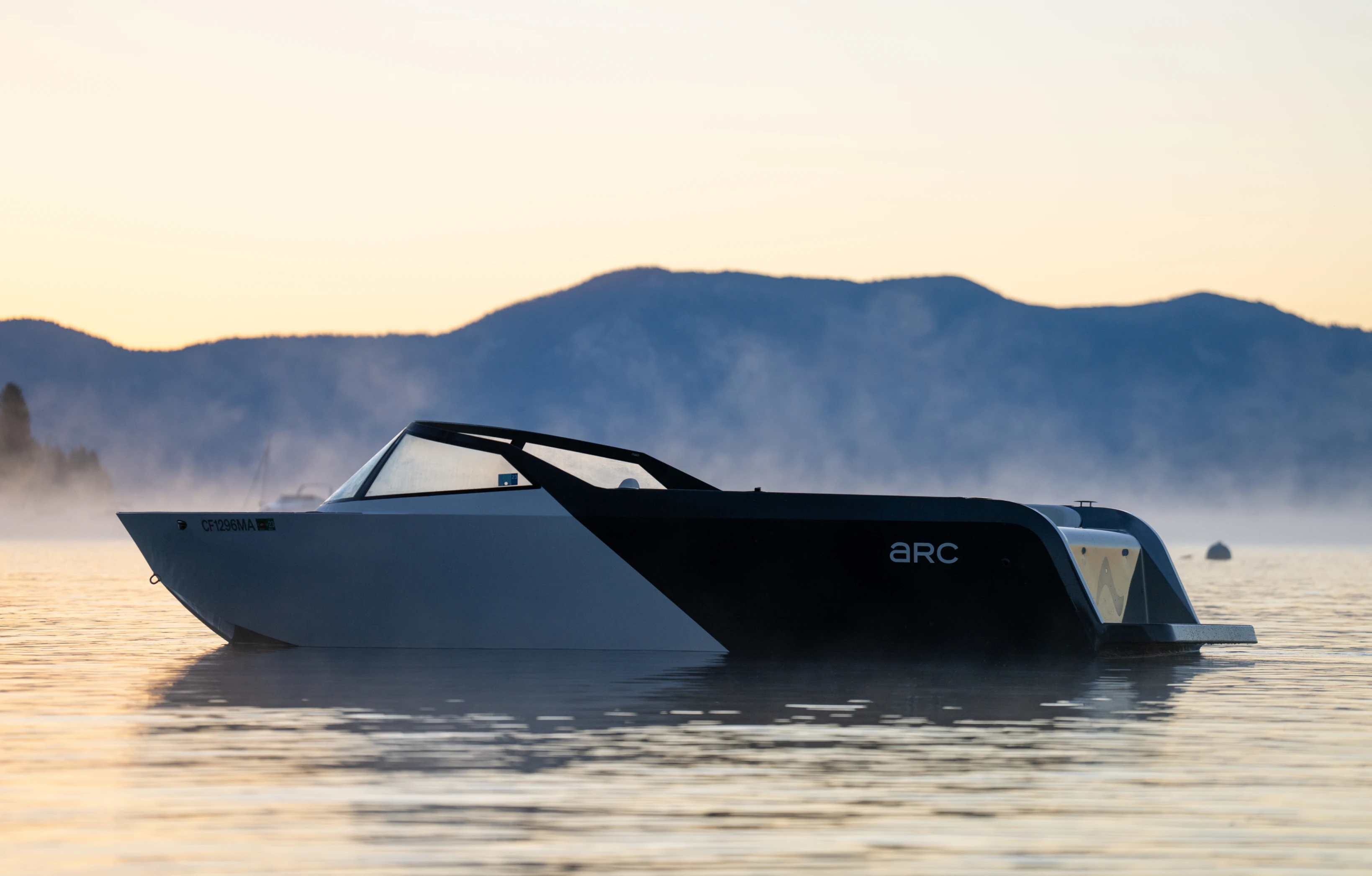 An Arc One boat sitting on a placid misty lake at sunrise