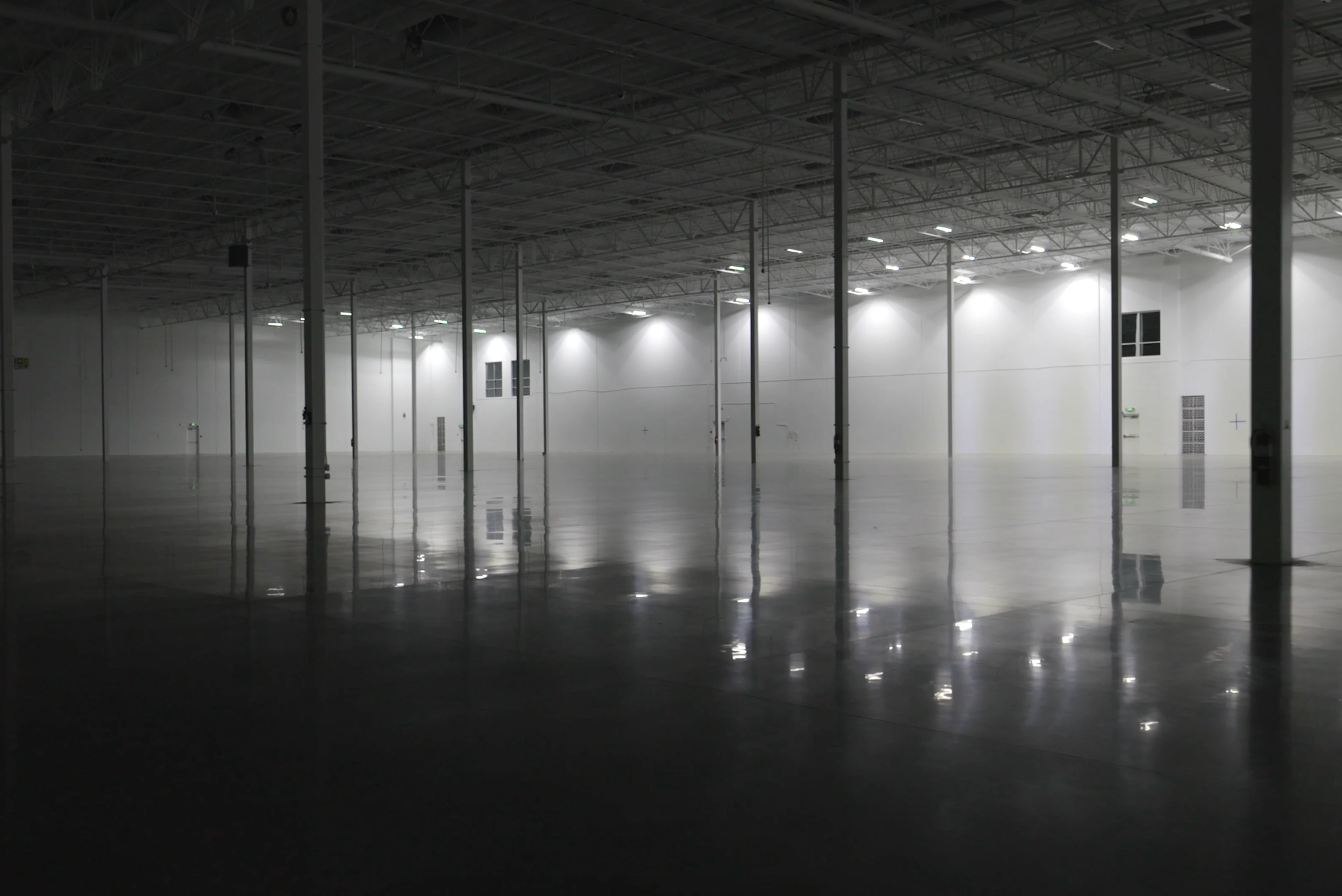 An alluring photo of a large partially lit open factory floor